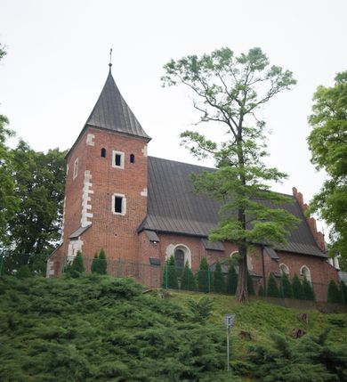 Zdjęcie nr 9: Na miejscu kościoła romańskiego, orientowany, dwunawowy, halowy; nawa południowa na rzucie prostokąta, na osi prezbiterium, dwuprzęsłowa, sklepiona kolebkowo z lunetami, na gurtach; nawa północna węższa od południowej, dwuprzęsłowa, sklepiona krzyżowo-żebrowo z kolistymi płaskorzeźbionymi zwornikami, jeden z literami ihs, drugi z literą s pod koroną. Prezbiterium prostokątne, dwuprzęsłowe, sklepione krzyżowo-żebrowo, z kolistymi zwornikami i profilowanymi wspornikami; przy nim od północy dawna zakrystia na rzucie prostokąta, sklepiona kolebkowo, otwarta do nawy wtórną arkadą, od wschodu nowa zakrystia na rzucie ośmioboku. Od zachodu przylega do nawy kwadratowa, czterokondygnacyjna wieża, z wieżyczką schodową w narożu północno-wschodnim, kruchtą w przyziemiu i chórem muzycznym na piętrze. Przy niej od północy drewniana piętrowa przybudówka mieszcząca w przyziemiu komorę bracką, na piętrze miech i kanał organowy. Przy nawie południowej od południa kwadratowa kruchta. Arkada tęczy zamknięta łukiem półkolistym, arkady do nawy północnej łukiem lekko zaostrzonym. Mury opięte przyporami, elewacje na cokole, z wzorami z zendrówki. Okna pierwotnie ostrołukowe, obustronnie rozglifione (niektóre zbarokizowane). Portale: zachodni, do kruchty pod wieżą, oraz do kruchty południowej, kamienne, prostokątne. Dachy dwuspadowe, pokryte blachą miedzianą. Zakrystia od wschodu przy prezbiterium wzniesiona na miejscu drewnianej kaplicy Ogrojcowej z XVIII wieku.