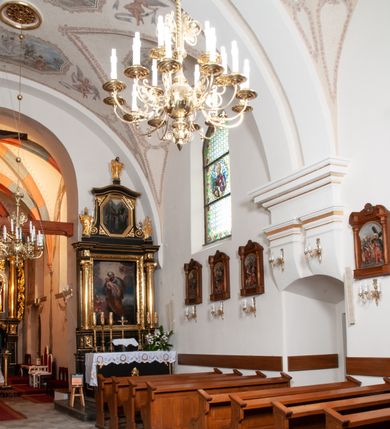 Zdjęcie nr 16: Na miejscu kościoła romańskiego, orientowany, dwunawowy, halowy; nawa południowa na rzucie prostokąta, na osi prezbiterium, dwuprzęsłowa, sklepiona kolebkowo z lunetami, na gurtach; nawa północna węższa od południowej, dwuprzęsłowa, sklepiona krzyżowo-żebrowo z kolistymi płaskorzeźbionymi zwornikami, jeden z literami ihs, drugi z literą s pod koroną. Prezbiterium prostokątne, dwuprzęsłowe, sklepione krzyżowo-żebrowo, z kolistymi zwornikami i profilowanymi wspornikami; przy nim od północy dawna zakrystia na rzucie prostokąta, sklepiona kolebkowo, otwarta do nawy wtórną arkadą, od wschodu nowa zakrystia na rzucie ośmioboku. Od zachodu przylega do nawy kwadratowa, czterokondygnacyjna wieża, z wieżyczką schodową w narożu północno-wschodnim, kruchtą w przyziemiu i chórem muzycznym na piętrze. Przy niej od północy drewniana piętrowa przybudówka mieszcząca w przyziemiu komorę bracką, na piętrze miech i kanał organowy. Przy nawie południowej od południa kwadratowa kruchta. Arkada tęczy zamknięta łukiem półkolistym, arkady do nawy północnej łukiem lekko zaostrzonym. Mury opięte przyporami, elewacje na cokole, z wzorami z zendrówki. Okna pierwotnie ostrołukowe, obustronnie rozglifione (niektóre zbarokizowane). Portale: zachodni, do kruchty pod wieżą, oraz do kruchty południowej, kamienne, prostokątne. Dachy dwuspadowe, pokryte blachą miedzianą. Zakrystia od wschodu przy prezbiterium wzniesiona na miejscu drewnianej kaplicy Ogrojcowej z XVIII wieku.