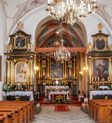 Zdjęcie nr 17: Na miejscu kościoła romańskiego, orientowany, dwunawowy, halowy; nawa południowa na rzucie prostokąta, na osi prezbiterium, dwuprzęsłowa, sklepiona kolebkowo z lunetami, na gurtach; nawa północna węższa od południowej, dwuprzęsłowa, sklepiona krzyżowo-żebrowo z kolistymi płaskorzeźbionymi zwornikami, jeden z literami ihs, drugi z literą s pod koroną. Prezbiterium prostokątne, dwuprzęsłowe, sklepione krzyżowo-żebrowo, z kolistymi zwornikami i profilowanymi wspornikami; przy nim od północy dawna zakrystia na rzucie prostokąta, sklepiona kolebkowo, otwarta do nawy wtórną arkadą, od wschodu nowa zakrystia na rzucie ośmioboku. Od zachodu przylega do nawy kwadratowa, czterokondygnacyjna wieża, z wieżyczką schodową w narożu północno-wschodnim, kruchtą w przyziemiu i chórem muzycznym na piętrze. Przy niej od północy drewniana piętrowa przybudówka mieszcząca w przyziemiu komorę bracką, na piętrze miech i kanał organowy. Przy nawie południowej od południa kwadratowa kruchta. Arkada tęczy zamknięta łukiem półkolistym, arkady do nawy północnej łukiem lekko zaostrzonym. Mury opięte przyporami, elewacje na cokole, z wzorami z zendrówki. Okna pierwotnie ostrołukowe, obustronnie rozglifione (niektóre zbarokizowane). Portale: zachodni, do kruchty pod wieżą, oraz do kruchty południowej, kamienne, prostokątne. Dachy dwuspadowe, pokryte blachą miedzianą. Zakrystia od wschodu przy prezbiterium wzniesiona na miejscu drewnianej kaplicy Ogrojcowej z XVIII wieku.