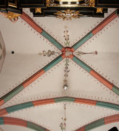 Zdjęcie nr 28: Na miejscu kościoła romańskiego, orientowany, dwunawowy, halowy; nawa południowa na rzucie prostokąta, na osi prezbiterium, dwuprzęsłowa, sklepiona kolebkowo z lunetami, na gurtach; nawa północna węższa od południowej, dwuprzęsłowa, sklepiona krzyżowo-żebrowo z kolistymi płaskorzeźbionymi zwornikami, jeden z literami ihs, drugi z literą s pod koroną. Prezbiterium prostokątne, dwuprzęsłowe, sklepione krzyżowo-żebrowo, z kolistymi zwornikami i profilowanymi wspornikami; przy nim od północy dawna zakrystia na rzucie prostokąta, sklepiona kolebkowo, otwarta do nawy wtórną arkadą, od wschodu nowa zakrystia na rzucie ośmioboku. Od zachodu przylega do nawy kwadratowa, czterokondygnacyjna wieża, z wieżyczką schodową w narożu północno-wschodnim, kruchtą w przyziemiu i chórem muzycznym na piętrze. Przy niej od północy drewniana piętrowa przybudówka mieszcząca w przyziemiu komorę bracką, na piętrze miech i kanał organowy. Przy nawie południowej od południa kwadratowa kruchta. Arkada tęczy zamknięta łukiem półkolistym, arkady do nawy północnej łukiem lekko zaostrzonym. Mury opięte przyporami, elewacje na cokole, z wzorami z zendrówki. Okna pierwotnie ostrołukowe, obustronnie rozglifione (niektóre zbarokizowane). Portale: zachodni, do kruchty pod wieżą, oraz do kruchty południowej, kamienne, prostokątne. Dachy dwuspadowe, pokryte blachą miedzianą. Zakrystia od wschodu przy prezbiterium wzniesiona na miejscu drewnianej kaplicy Ogrojcowej z XVIII wieku.