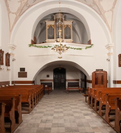 Zdjęcie nr 35: Na miejscu kościoła romańskiego, orientowany, dwunawowy, halowy; nawa południowa na rzucie prostokąta, na osi prezbiterium, dwuprzęsłowa, sklepiona kolebkowo z lunetami, na gurtach; nawa północna węższa od południowej, dwuprzęsłowa, sklepiona krzyżowo-żebrowo z kolistymi płaskorzeźbionymi zwornikami, jeden z literami ihs, drugi z literą s pod koroną. Prezbiterium prostokątne, dwuprzęsłowe, sklepione krzyżowo-żebrowo, z kolistymi zwornikami i profilowanymi wspornikami; przy nim od północy dawna zakrystia na rzucie prostokąta, sklepiona kolebkowo, otwarta do nawy wtórną arkadą, od wschodu nowa zakrystia na rzucie ośmioboku. Od zachodu przylega do nawy kwadratowa, czterokondygnacyjna wieża, z wieżyczką schodową w narożu północno-wschodnim, kruchtą w przyziemiu i chórem muzycznym na piętrze. Przy niej od północy drewniana piętrowa przybudówka mieszcząca w przyziemiu komorę bracką, na piętrze miech i kanał organowy. Przy nawie południowej od południa kwadratowa kruchta. Arkada tęczy zamknięta łukiem półkolistym, arkady do nawy północnej łukiem lekko zaostrzonym. Mury opięte przyporami, elewacje na cokole, z wzorami z zendrówki. Okna pierwotnie ostrołukowe, obustronnie rozglifione (niektóre zbarokizowane). Portale: zachodni, do kruchty pod wieżą, oraz do kruchty południowej, kamienne, prostokątne. Dachy dwuspadowe, pokryte blachą miedzianą. Zakrystia od wschodu przy prezbiterium wzniesiona na miejscu drewnianej kaplicy Ogrojcowej z XVIII wieku.