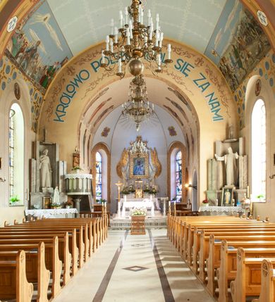 Zdjęcie nr 7: Kościół murowany, na kamiennym podmurowaniu, jednonawowy, na planie krzyża. Nawa na rzucie wydłużonego prostokąta, z węższym, jednoprzęsłowym prezbiterium zamkniętym trójbocznie, flankowanym dwoma kwadratowymi aneksami – zakrystią i kaplicą. Od południowego-zachodu dostawiona wieża na planie kwadratu z uskokowym zwężeniem ostatniej kondygnacji, z kruchtą w przyziemiu, ujęta dwiema wieżyczkami na planie ściętego koła, w południowej kręcone schody, w północnej schowek oraz dwoma otwartymi na zewnątrz arkadą aneksami na planie kwadratu z wejściami bocznymi do świątyni. Wnętrze nakryte sklepieniem kolebkowym z dwoma gurtami opadającymi na cztery półfilary. Otwór tęczowy w formie leżącego prostokąta zamkniętego łukiem półkolistym. W południowo-zachodniej części nawy zawieszony parapet chóru muzycznego o wybrzuszonej części środkowej balustrady. Posadzka betonowa, pokryta płytami kamiennymi. Fasada wieżowa, bez podziału na kondygnacje, w narożach ujęta kamiennymi szkarpami. Na osi portal wejściowy w formie kwadratu zamkniętego łukiem półkolistym, z dwuskrzydłowymi drzwiami, nakryty daszkiem okapowym. Nad nim okno witrażowe w formie koła. Wieża przepruta z trzech stron oknami w formie wydłużonego prostokąta zamkniętego półkoliście oraz w najwyższej części z czterech stron potrójnymi, arkadkowymi oknami. Wieżyczki przeprute niewielkimi, okrągłymi okienkami. Elewacje północna i południowa, ujęte we frontowych narożach kamiennymi szkarpami, przeprute trzema oknami witrażowymi w formie wydłużonego prostokąta zamkniętego półkoliście. Kaplica i zakrystia z jednym oknem o kształcie kwadratu zamkniętego łukiem półkolistym. Elewacja północno-wschodnia z dwoma oknami. Wieża nakryta dachem wieżowym kopulastym z latarnią zakończoną krzyżem, wieżyczki daszkami stożkowymi, a aneksy pulpitowymi. Dach nad nawą dwuspadowy z sześcioboczną wieżyczką na sygnaturkę nakrytą daszkiem wieżowym, prezbiterium niższe, przykryte dachem wielospadowym, kaplica i zakrystia dwuspadowym. 