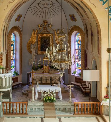 Zdjęcie nr 9: Kościół murowany, na kamiennym podmurowaniu, jednonawowy, na planie krzyża. Nawa na rzucie wydłużonego prostokąta, z węższym, jednoprzęsłowym prezbiterium zamkniętym trójbocznie, flankowanym dwoma kwadratowymi aneksami – zakrystią i kaplicą. Od południowego-zachodu dostawiona wieża na planie kwadratu z uskokowym zwężeniem ostatniej kondygnacji, z kruchtą w przyziemiu, ujęta dwiema wieżyczkami na planie ściętego koła, w południowej kręcone schody, w północnej schowek oraz dwoma otwartymi na zewnątrz arkadą aneksami na planie kwadratu z wejściami bocznymi do świątyni. Wnętrze nakryte sklepieniem kolebkowym z dwoma gurtami opadającymi na cztery półfilary. Otwór tęczowy w formie leżącego prostokąta zamkniętego łukiem półkolistym. W południowo-zachodniej części nawy zawieszony parapet chóru muzycznego o wybrzuszonej części środkowej balustrady. Posadzka betonowa, pokryta płytami kamiennymi. Fasada wieżowa, bez podziału na kondygnacje, w narożach ujęta kamiennymi szkarpami. Na osi portal wejściowy w formie kwadratu zamkniętego łukiem półkolistym, z dwuskrzydłowymi drzwiami, nakryty daszkiem okapowym. Nad nim okno witrażowe w formie koła. Wieża przepruta z trzech stron oknami w formie wydłużonego prostokąta zamkniętego półkoliście oraz w najwyższej części z czterech stron potrójnymi, arkadkowymi oknami. Wieżyczki przeprute niewielkimi, okrągłymi okienkami. Elewacje północna i południowa, ujęte we frontowych narożach kamiennymi szkarpami, przeprute trzema oknami witrażowymi w formie wydłużonego prostokąta zamkniętego półkoliście. Kaplica i zakrystia z jednym oknem o kształcie kwadratu zamkniętego łukiem półkolistym. Elewacja północno-wschodnia z dwoma oknami. Wieża nakryta dachem wieżowym kopulastym z latarnią zakończoną krzyżem, wieżyczki daszkami stożkowymi, a aneksy pulpitowymi. Dach nad nawą dwuspadowy z sześcioboczną wieżyczką na sygnaturkę nakrytą daszkiem wieżowym, prezbiterium niższe, przykryte dachem wielospadowym, kaplica i zakrystia dwuspadowym. 