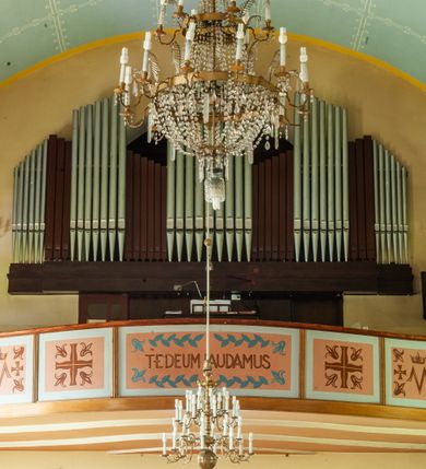 Zdjęcie nr 12: Kościół murowany, na kamiennym podmurowaniu, jednonawowy, na planie krzyża. Nawa na rzucie wydłużonego prostokąta, z węższym, jednoprzęsłowym prezbiterium zamkniętym trójbocznie, flankowanym dwoma kwadratowymi aneksami – zakrystią i kaplicą. Od południowego-zachodu dostawiona wieża na planie kwadratu z uskokowym zwężeniem ostatniej kondygnacji, z kruchtą w przyziemiu, ujęta dwiema wieżyczkami na planie ściętego koła, w południowej kręcone schody, w północnej schowek oraz dwoma otwartymi na zewnątrz arkadą aneksami na planie kwadratu z wejściami bocznymi do świątyni. Wnętrze nakryte sklepieniem kolebkowym z dwoma gurtami opadającymi na cztery półfilary. Otwór tęczowy w formie leżącego prostokąta zamkniętego łukiem półkolistym. W południowo-zachodniej części nawy zawieszony parapet chóru muzycznego o wybrzuszonej części środkowej balustrady. Posadzka betonowa, pokryta płytami kamiennymi. Fasada wieżowa, bez podziału na kondygnacje, w narożach ujęta kamiennymi szkarpami. Na osi portal wejściowy w formie kwadratu zamkniętego łukiem półkolistym, z dwuskrzydłowymi drzwiami, nakryty daszkiem okapowym. Nad nim okno witrażowe w formie koła. Wieża przepruta z trzech stron oknami w formie wydłużonego prostokąta zamkniętego półkoliście oraz w najwyższej części z czterech stron potrójnymi, arkadkowymi oknami. Wieżyczki przeprute niewielkimi, okrągłymi okienkami. Elewacje północna i południowa, ujęte we frontowych narożach kamiennymi szkarpami, przeprute trzema oknami witrażowymi w formie wydłużonego prostokąta zamkniętego półkoliście. Kaplica i zakrystia z jednym oknem o kształcie kwadratu zamkniętego łukiem półkolistym. Elewacja północno-wschodnia z dwoma oknami. Wieża nakryta dachem wieżowym kopulastym z latarnią zakończoną krzyżem, wieżyczki daszkami stożkowymi, a aneksy pulpitowymi. Dach nad nawą dwuspadowy z sześcioboczną wieżyczką na sygnaturkę nakrytą daszkiem wieżowym, prezbiterium niższe, przykryte dachem wielospadowym, kaplica i zakrystia dwuspadowym. 