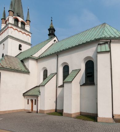 Zdjęcie nr 7: Kościół orientowany, murowany, trójnawowy, z prezbiterium zamkniętym trójbocznie, zakrystią od północy i kruchtą od południa. Do naw przylegają kaplice: większa od północy i mniejsza od południa. Dwie kolejne kaplice przylegają do boków wieży. Ściany wnętrza gładkie, pokryte polichromią imitującą podziały i obramienia, dekorację ornamentalną i sceny iluzjonistyczne na stropach, utrzymane w chłodnej biało-niebiesko-różowej tonacji z dodatkiem żółtego. Na stropie prezbiterium scena Zwiastowania, na stropie nawy Zesłania Ducha Świętego. Od zachodu chór muzyczny wsparty na dwóch filarach z balustradą pokrytą polichromią. Prezbiterium i nawa główna nakryte stropami, nad prezbiterium o przekroju spłaszczonej kolebki, nad nawą płaski, z szerokimi fasetami, zakrystia sklepiona kolebkowo, kruchta i kaplice wschodnie krzyżowo. Nawę, prezbiterium i część kaplic doświetlają okna w kształcie stojącego prostokąta zamkniętego łukiem pełnym, pozostałe zamknięte łukiem odcinkowym lub kwadratowe. Główne wejście i dwa boczne od zachodu, kolejne do przedsionka od północy i do kruchty od południa. Fasada z wieżą na osi, poprzedzona portykiem wspartym na filarach, z trójkątnym szczytem zwieńczonym krzyżem łacińskim. Fasada jednokondygnacyjna, przechodząca w masyw wieży. Kondygnację przepruwają trzy okna i jest zamknięta gzymsem wyniesionym na środku w łuk. Wieńczący ją trójkątny szczyt wtapia się w kondygnację wieży o gładkich elewacjach przeprutych jedynie niewielkimi oknami i tarczami zegarów. Ostatnia kondygnacja jest ujęta gzymsami i dekorowana fryzem arkadowym, którego arkady wykonano z nietynkowanej cegły. Zwieńczenie rozbudowane składa się z iglicy i ustawionych wokół niej, w narożach małych, dwukondygnacyjnych wieżyczek zamkniętych dachami stożkowymi. Wieżyczki połączono podwójnymi arkadami, których łuki wykonano z nietynkowanej cegły, tak samo jak górne kondygnacje wieżyczek. Elewacje kościoła gładkie, na niskim, kamiennym cokole, od wschodu opięte szkarpami. Prezbiterium i nawę przekrywają osobne dachy dwuspadowe, na kalenicy nawy wieżyczka na sygnaturkę, cztery kaplice i portyk nakrywają dachy trójpołaciowe, zakrystię i nawy boczne pulpitowe. 
Jedyne zachowane elementy wyposażenia sprzed pożaru w 1815 roku to fragment osiemnastowiecznej polichromii przedstawiającej dwóch aniołów z narzędziami męki i przedmioty nawiązujące do tego wydarzenia oraz gotycki portal do zakrystii wraz z żelaznymi, kutymi drzwiami. 
