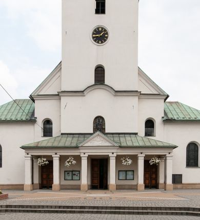 Zdjęcie nr 3: Kościół orientowany, murowany, trójnawowy, z prezbiterium zamkniętym trójbocznie, zakrystią od północy i kruchtą od południa. Do naw przylegają kaplice: większa od północy i mniejsza od południa. Dwie kolejne kaplice przylegają do boków wieży. Ściany wnętrza gładkie, pokryte polichromią imitującą podziały i obramienia, dekorację ornamentalną i sceny iluzjonistyczne na stropach, utrzymane w chłodnej biało-niebiesko-różowej tonacji z dodatkiem żółtego. Na stropie prezbiterium scena Zwiastowania, na stropie nawy Zesłania Ducha Świętego. Od zachodu chór muzyczny wsparty na dwóch filarach z balustradą pokrytą polichromią. Prezbiterium i nawa główna nakryte stropami, nad prezbiterium o przekroju spłaszczonej kolebki, nad nawą płaski, z szerokimi fasetami, zakrystia sklepiona kolebkowo, kruchta i kaplice wschodnie krzyżowo. Nawę, prezbiterium i część kaplic doświetlają okna w kształcie stojącego prostokąta zamkniętego łukiem pełnym, pozostałe zamknięte łukiem odcinkowym lub kwadratowe. Główne wejście i dwa boczne od zachodu, kolejne do przedsionka od północy i do kruchty od południa. Fasada z wieżą na osi, poprzedzona portykiem wspartym na filarach, z trójkątnym szczytem zwieńczonym krzyżem łacińskim. Fasada jednokondygnacyjna, przechodząca w masyw wieży. Kondygnację przepruwają trzy okna i jest zamknięta gzymsem wyniesionym na środku w łuk. Wieńczący ją trójkątny szczyt wtapia się w kondygnację wieży o gładkich elewacjach przeprutych jedynie niewielkimi oknami i tarczami zegarów. Ostatnia kondygnacja jest ujęta gzymsami i dekorowana fryzem arkadowym, którego arkady wykonano z nietynkowanej cegły. Zwieńczenie rozbudowane składa się z iglicy i ustawionych wokół niej, w narożach małych, dwukondygnacyjnych wieżyczek zamkniętych dachami stożkowymi. Wieżyczki połączono podwójnymi arkadami, których łuki wykonano z nietynkowanej cegły, tak samo jak górne kondygnacje wieżyczek. Elewacje kościoła gładkie, na niskim, kamiennym cokole, od wschodu opięte szkarpami. Prezbiterium i nawę przekrywają osobne dachy dwuspadowe, na kalenicy nawy wieżyczka na sygnaturkę, cztery kaplice i portyk nakrywają dachy trójpołaciowe, zakrystię i nawy boczne pulpitowe. 
Jedyne zachowane elementy wyposażenia sprzed pożaru w 1815 roku to fragment osiemnastowiecznej polichromii przedstawiającej dwóch aniołów z narzędziami męki i przedmioty nawiązujące do tego wydarzenia oraz gotycki portal do zakrystii wraz z żelaznymi, kutymi drzwiami. 
