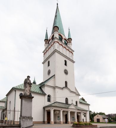 Zdjęcie nr 1: Kościół orientowany, murowany, trójnawowy, z prezbiterium zamkniętym trójbocznie, zakrystią od północy i kruchtą od południa. Do naw przylegają kaplice: większa od północy i mniejsza od południa. Dwie kolejne kaplice przylegają do boków wieży. Ściany wnętrza gładkie, pokryte polichromią imitującą podziały i obramienia, dekorację ornamentalną i sceny iluzjonistyczne na stropach, utrzymane w chłodnej biało-niebiesko-różowej tonacji z dodatkiem żółtego. Na stropie prezbiterium scena Zwiastowania, na stropie nawy Zesłania Ducha Świętego. Od zachodu chór muzyczny wsparty na dwóch filarach z balustradą pokrytą polichromią. Prezbiterium i nawa główna nakryte stropami, nad prezbiterium o przekroju spłaszczonej kolebki, nad nawą płaski, z szerokimi fasetami, zakrystia sklepiona kolebkowo, kruchta i kaplice wschodnie krzyżowo. Nawę, prezbiterium i część kaplic doświetlają okna w kształcie stojącego prostokąta zamkniętego łukiem pełnym, pozostałe zamknięte łukiem odcinkowym lub kwadratowe. Główne wejście i dwa boczne od zachodu, kolejne do przedsionka od północy i do kruchty od południa. Fasada z wieżą na osi, poprzedzona portykiem wspartym na filarach, z trójkątnym szczytem zwieńczonym krzyżem łacińskim. Fasada jednokondygnacyjna, przechodząca w masyw wieży. Kondygnację przepruwają trzy okna i jest zamknięta gzymsem wyniesionym na środku w łuk. Wieńczący ją trójkątny szczyt wtapia się w kondygnację wieży o gładkich elewacjach przeprutych jedynie niewielkimi oknami i tarczami zegarów. Ostatnia kondygnacja jest ujęta gzymsami i dekorowana fryzem arkadowym, którego arkady wykonano z nietynkowanej cegły. Zwieńczenie rozbudowane składa się z iglicy i ustawionych wokół niej, w narożach małych, dwukondygnacyjnych wieżyczek zamkniętych dachami stożkowymi. Wieżyczki połączono podwójnymi arkadami, których łuki wykonano z nietynkowanej cegły, tak samo jak górne kondygnacje wieżyczek. Elewacje kościoła gładkie, na niskim, kamiennym cokole, od wschodu opięte szkarpami. Prezbiterium i nawę przekrywają osobne dachy dwuspadowe, na kalenicy nawy wieżyczka na sygnaturkę, cztery kaplice i portyk nakrywają dachy trójpołaciowe, zakrystię i nawy boczne pulpitowe. 
Jedyne zachowane elementy wyposażenia sprzed pożaru w 1815 roku to fragment osiemnastowiecznej polichromii przedstawiającej dwóch aniołów z narzędziami męki i przedmioty nawiązujące do tego wydarzenia oraz gotycki portal do zakrystii wraz z żelaznymi, kutymi drzwiami. 
