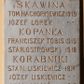 Zdjęcie nr 1: Tablica pamiątkowa z jasnego kamienia w kształcie bardzo wydłużonego, stojącego prostokąta, z kutym, złoconym napisem „SKAWINA / TOM(ASZ) HACHORKIEWICZ 1919 / JÓZEF LOREK / KOPANKA / FRANCISZEK TOBIS 1915 / STAI(ISŁAW) OSTROWSKI 1918 / KORABNIKI / STAN(ISŁAW) LISKIEWICZ 1914 / JÓZEF LISKIEWICZ / JAN KŁYŚ 1919 / RZOZÓW / JÓZEF PLANTA 1914 / JAN KUBAS 1915 / MICHAŁ MADEJ / ANTONI KLIMAS 1918 / MICHAŁ PUTAJ / SAMBOREK / PIOTR HABAS 1917 / SIDZINA / JAN STYRYLSKI 1914 / ANDRZEJ BYK / JÓZEF CHMURA / MICHAŁ BALON 1915 / FRANCISZEK BYK 1919”. W narożach ozdobne rozetki maskują miejsca mocowania.