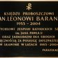 Zdjęcie nr 1: Tablica w kształcie leżącego prostokąta z kutym, złoconym napisem poniżej chrystogramu „KSIĘDZU PROBOSZCZOWI / KS(IĘDZU) KAN(ONIKOWI) LEONOWI BARANOWI / 1933-2004 / ZAŁOŻYCIELOWI ZESPOŁU KATOLICKICH SZKÓŁ / im(ienia) JANA PAWŁA II / ORAZ JADŁODAJNI DLA UBOGICH / Z WDZIĘCZNOŚCIĄ ZA POSŁUGĘ DUSZPASTERSKĄ / W SKAWINIE W LATACH 1983-2004 / PARAFIANIE”. W narożach dekoracyjne rozetki maskują miejsca mocowania. 