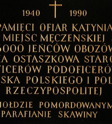 Zdjęcie nr 1: Tablica z czarnego kamienia w kształcie leżącego prostokąta z majuskułowym, złoconym napisem na środku „1940+ 1990 / PAMIĘCI OFIAR KATYNIA / I INNYCH MIEJSC MĘCZEŃSKIEJ ŚMIERCI / 15000 JEŃCÓW OBOZÓW / KOZIELSKA OSTASZKOWA STAROBIELSKA / OFICERÓW PODOFICERÓW / WOJSKA POLSKIEGO I POLICJI / RZECZYPOSPOLITEJ / W HOŁDZIE POMORDOWYANYM / PARAFIANIE SKAWINY”.