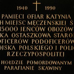 Zdjęcie nr 1: Tablica z czarnego kamienia w kształcie leżącego prostokąta z majuskułowym, złoconym napisem na środku „1940+ 1990 / PAMIĘCI OFIAR KATYNIA / I INNYCH MIEJSC MĘCZEŃSKIEJ ŚMIERCI / 15000 JEŃCÓW OBOZÓW / KOZIELSKA OSTASZKOWA STAROBIELSKA / OFICERÓW PODOFICERÓW / WOJSKA POLSKIEGO I POLICJI / RZECZYPOSPOLITEJ / W HOŁDZIE POMORDOWYANYM / PARAFIANIE SKAWINY”.