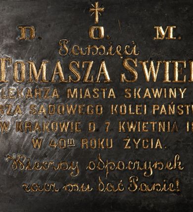 Zdjęcie nr 1: Tablica w kształcie leżącego prostokąta obwiedziona ramką z kwadratami w narożach. Na środku, poniżej krzyża łacińskiego złocona inskrypcja „D(EO) O(PTIMO) M(AXIMO) / Pamięci / D(okto)ra TOMASZA  SWIERZA / LEKARZA MIASTA SKAWINY / LEKARZA SĄDOWEGO KOLEI PAŃSTWOWEJ / ZM(ARŁEGO) W KRAKOWIE D(NIA) 7. KWIETNIA 1888. / W 40(ty)m ROKU ŻYCIA / Wieczny odpoczynek / racz mu dać Panie!”. 