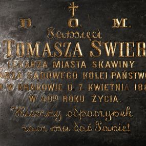 Zdjęcie nr 1: Tablica w kształcie leżącego prostokąta obwiedziona ramką z kwadratami w narożach. Na środku, poniżej krzyża łacińskiego złocona inskrypcja „D(EO) O(PTIMO) M(AXIMO) / Pamięci / D(okto)ra TOMASZA  SWIERZA / LEKARZA MIASTA SKAWINY / LEKARZA SĄDOWEGO KOLEI PAŃSTWOWEJ / ZM(ARŁEGO) W KRAKOWIE D(NIA) 7. KWIETNIA 1888. / W 40(ty)m ROKU ŻYCIA / Wieczny odpoczynek / racz mu dać Panie!”. 