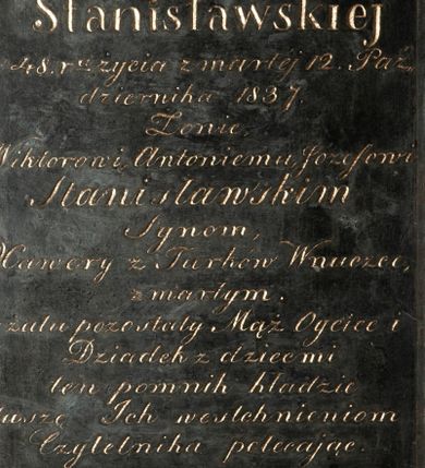 Zdjęcie nr 1: Kamienna płyta w kształcie stojącego prostokąta z wykutą i pozłoconą inskrypcją „D(EO) O(PTIMO) M(AXIMO) / Possesorce Rzozowa / Zofii z Mendelowiczów / Stanisławskiej / w 48. r(ok)u życia zmarłej 12. Paź/dziernika 1837. / Żonie, / Wiktorowi, Antoniemu, Józefowi / Stanisławskim / Synom, / Xawery z Turków Wnuczce, / zmarłym. / w żalu pozostały Mąż Oyciec i / Dziadek z dziećmi / ten pomnik kładzie / duszę Ich westchnieniom / Czytelnika polecając”. Napis obwiedziono ramką wyciętą w narożach, aby zrobić miejsce na dekoracyjne rozetki. 