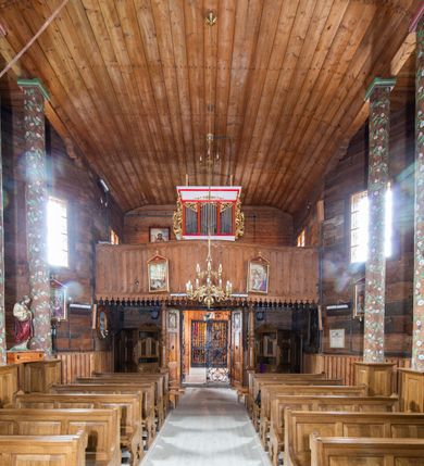 Zdjęcie nr 8: Kościół św. Joachima w Skawinkach usytuowany jest w centrum wsi, na zachód od głównej drogi prowadzącej z Palczy do Kalwarii Zebrzydowskiej. Teren przykościelny jest usytuowany na wysokim wzniesieniu, do którego prowadzą trzy wejścia, jedno przez schody, drugie przez obszerny wjazd od strony południowej.

Kościół skierowany na zachód, drewniany o konstrukcji zrębowej, na rzucie krzyża greckiego ze ściętymi kątami międzyramiennymi.  Przy prezbiterium zakrystia. Strop wsparty na czterech parach słupów, ustawionych w krzyżu kościoła, w licu ścian ramienia wschodniego i zachodniego. Belka tęczy prosta, profilowana na kroksztynach, na niej Grupa Ukrzyżowania. Świątynia połączona za pomocą kruchty z wieżą o konstrukcji słupowej, na planie kwadratu z nadwieszoną izbicą, nakryta dachem namiotowym, ściany dzwonnicy opasane mniej więcej w połowie wysokości pulpitowym daszkiem, zlewającym się po bokach z siodłowym dachem kruchty. Do kościoła prowadzi główne wejście w przedsionku od strony południowej. Wnętrze świątyni oświetlają prostokątne okna. Dach nakryty gontem, na skrzyżowaniu ramiona krzyża greckiego wystawiona wieżyczka na sygnaturkę z latarnią. Ściany na zewnątrz pokryte szalunkiem pionowym.
