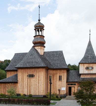 Zdjęcie nr 12: Kościół św. Joachima w Skawinkach usytuowany jest w centrum wsi, na zachód od głównej drogi prowadzącej z Palczy do Kalwarii Zebrzydowskiej. Teren przykościelny jest usytuowany na wysokim wzniesieniu, do którego prowadzą trzy wejścia, jedno przez schody, drugie przez obszerny wjazd od strony południowej.

Kościół skierowany na zachód, drewniany o konstrukcji zrębowej, na rzucie krzyża greckiego ze ściętymi kątami międzyramiennymi.  Przy prezbiterium zakrystia. Strop wsparty na czterech parach słupów, ustawionych w krzyżu kościoła, w licu ścian ramienia wschodniego i zachodniego. Belka tęczy prosta, profilowana na kroksztynach, na niej Grupa Ukrzyżowania. Świątynia połączona za pomocą kruchty z wieżą o konstrukcji słupowej, na planie kwadratu z nadwieszoną izbicą, nakryta dachem namiotowym, ściany dzwonnicy opasane mniej więcej w połowie wysokości pulpitowym daszkiem, zlewającym się po bokach z siodłowym dachem kruchty. Do kościoła prowadzi główne wejście w przedsionku od strony południowej. Wnętrze świątyni oświetlają prostokątne okna. Dach nakryty gontem, na skrzyżowaniu ramiona krzyża greckiego wystawiona wieżyczka na sygnaturkę z latarnią. Ściany na zewnątrz pokryte szalunkiem pionowym.
