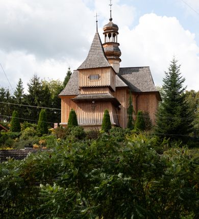 Zdjęcie nr 14: Kościół św. Joachima w Skawinkach usytuowany jest w centrum wsi, na zachód od głównej drogi prowadzącej z Palczy do Kalwarii Zebrzydowskiej. Teren przykościelny jest usytuowany na wysokim wzniesieniu, do którego prowadzą trzy wejścia, jedno przez schody, drugie przez obszerny wjazd od strony południowej.

Kościół skierowany na zachód, drewniany o konstrukcji zrębowej, na rzucie krzyża greckiego ze ściętymi kątami międzyramiennymi.  Przy prezbiterium zakrystia. Strop wsparty na czterech parach słupów, ustawionych w krzyżu kościoła, w licu ścian ramienia wschodniego i zachodniego. Belka tęczy prosta, profilowana na kroksztynach, na niej Grupa Ukrzyżowania. Świątynia połączona za pomocą kruchty z wieżą o konstrukcji słupowej, na planie kwadratu z nadwieszoną izbicą, nakryta dachem namiotowym, ściany dzwonnicy opasane mniej więcej w połowie wysokości pulpitowym daszkiem, zlewającym się po bokach z siodłowym dachem kruchty. Do kościoła prowadzi główne wejście w przedsionku od strony południowej. Wnętrze świątyni oświetlają prostokątne okna. Dach nakryty gontem, na skrzyżowaniu ramiona krzyża greckiego wystawiona wieżyczka na sygnaturkę z latarnią. Ściany na zewnątrz pokryte szalunkiem pionowym.
