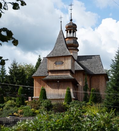 Zdjęcie nr 19: Kościół św. Joachima w Skawinkach usytuowany jest w centrum wsi, na zachód od głównej drogi prowadzącej z Palczy do Kalwarii Zebrzydowskiej. Teren przykościelny jest usytuowany na wysokim wzniesieniu, do którego prowadzą trzy wejścia, jedno przez schody, drugie przez obszerny wjazd od strony południowej.

Kościół skierowany na zachód, drewniany o konstrukcji zrębowej, na rzucie krzyża greckiego ze ściętymi kątami międzyramiennymi.  Przy prezbiterium zakrystia. Strop wsparty na czterech parach słupów, ustawionych w krzyżu kościoła, w licu ścian ramienia wschodniego i zachodniego. Belka tęczy prosta, profilowana na kroksztynach, na niej Grupa Ukrzyżowania. Świątynia połączona za pomocą kruchty z wieżą o konstrukcji słupowej, na planie kwadratu z nadwieszoną izbicą, nakryta dachem namiotowym, ściany dzwonnicy opasane mniej więcej w połowie wysokości pulpitowym daszkiem, zlewającym się po bokach z siodłowym dachem kruchty. Do kościoła prowadzi główne wejście w przedsionku od strony południowej. Wnętrze świątyni oświetlają prostokątne okna. Dach nakryty gontem, na skrzyżowaniu ramiona krzyża greckiego wystawiona wieżyczka na sygnaturkę z latarnią. Ściany na zewnątrz pokryte szalunkiem pionowym.
