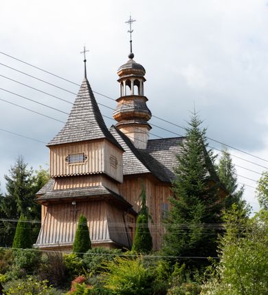 Zdjęcie nr 20: Kościół św. Joachima w Skawinkach usytuowany jest w centrum wsi, na zachód od głównej drogi prowadzącej z Palczy do Kalwarii Zebrzydowskiej. Teren przykościelny jest usytuowany na wysokim wzniesieniu, do którego prowadzą trzy wejścia, jedno przez schody, drugie przez obszerny wjazd od strony południowej.

Kościół skierowany na zachód, drewniany o konstrukcji zrębowej, na rzucie krzyża greckiego ze ściętymi kątami międzyramiennymi.  Przy prezbiterium zakrystia. Strop wsparty na czterech parach słupów, ustawionych w krzyżu kościoła, w licu ścian ramienia wschodniego i zachodniego. Belka tęczy prosta, profilowana na kroksztynach, na niej Grupa Ukrzyżowania. Świątynia połączona za pomocą kruchty z wieżą o konstrukcji słupowej, na planie kwadratu z nadwieszoną izbicą, nakryta dachem namiotowym, ściany dzwonnicy opasane mniej więcej w połowie wysokości pulpitowym daszkiem, zlewającym się po bokach z siodłowym dachem kruchty. Do kościoła prowadzi główne wejście w przedsionku od strony południowej. Wnętrze świątyni oświetlają prostokątne okna. Dach nakryty gontem, na skrzyżowaniu ramiona krzyża greckiego wystawiona wieżyczka na sygnaturkę z latarnią. Ściany na zewnątrz pokryte szalunkiem pionowym.
