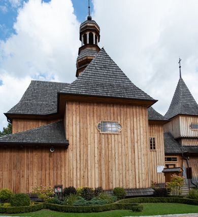 Zdjęcie nr 23: Kościół św. Joachima w Skawinkach usytuowany jest w centrum wsi, na zachód od głównej drogi prowadzącej z Palczy do Kalwarii Zebrzydowskiej. Teren przykościelny jest usytuowany na wysokim wzniesieniu, do którego prowadzą trzy wejścia, jedno przez schody, drugie przez obszerny wjazd od strony południowej.

Kościół skierowany na zachód, drewniany o konstrukcji zrębowej, na rzucie krzyża greckiego ze ściętymi kątami międzyramiennymi.  Przy prezbiterium zakrystia. Strop wsparty na czterech parach słupów, ustawionych w krzyżu kościoła, w licu ścian ramienia wschodniego i zachodniego. Belka tęczy prosta, profilowana na kroksztynach, na niej Grupa Ukrzyżowania. Świątynia połączona za pomocą kruchty z wieżą o konstrukcji słupowej, na planie kwadratu z nadwieszoną izbicą, nakryta dachem namiotowym, ściany dzwonnicy opasane mniej więcej w połowie wysokości pulpitowym daszkiem, zlewającym się po bokach z siodłowym dachem kruchty. Do kościoła prowadzi główne wejście w przedsionku od strony południowej. Wnętrze świątyni oświetlają prostokątne okna. Dach nakryty gontem, na skrzyżowaniu ramiona krzyża greckiego wystawiona wieżyczka na sygnaturkę z latarnią. Ściany na zewnątrz pokryte szalunkiem pionowym.
