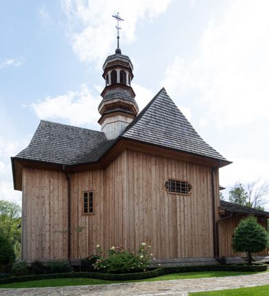 Zdjęcie nr 25: Kościół św. Joachima w Skawinkach usytuowany jest w centrum wsi, na zachód od głównej drogi prowadzącej z Palczy do Kalwarii Zebrzydowskiej. Teren przykościelny jest usytuowany na wysokim wzniesieniu, do którego prowadzą trzy wejścia, jedno przez schody, drugie przez obszerny wjazd od strony południowej.

Kościół skierowany na zachód, drewniany o konstrukcji zrębowej, na rzucie krzyża greckiego ze ściętymi kątami międzyramiennymi.  Przy prezbiterium zakrystia. Strop wsparty na czterech parach słupów, ustawionych w krzyżu kościoła, w licu ścian ramienia wschodniego i zachodniego. Belka tęczy prosta, profilowana na kroksztynach, na niej Grupa Ukrzyżowania. Świątynia połączona za pomocą kruchty z wieżą o konstrukcji słupowej, na planie kwadratu z nadwieszoną izbicą, nakryta dachem namiotowym, ściany dzwonnicy opasane mniej więcej w połowie wysokości pulpitowym daszkiem, zlewającym się po bokach z siodłowym dachem kruchty. Do kościoła prowadzi główne wejście w przedsionku od strony południowej. Wnętrze świątyni oświetlają prostokątne okna. Dach nakryty gontem, na skrzyżowaniu ramiona krzyża greckiego wystawiona wieżyczka na sygnaturkę z latarnią. Ściany na zewnątrz pokryte szalunkiem pionowym.
