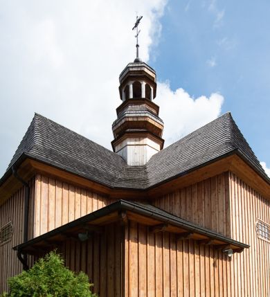 Zdjęcie nr 1: Kościół św. Joachima w Skawinkach usytuowany jest w centrum wsi, na zachód od głównej drogi prowadzącej z Palczy do Kalwarii Zebrzydowskiej. Teren przykościelny jest usytuowany na wysokim wzniesieniu, do którego prowadzą trzy wejścia, jedno przez schody, drugie przez obszerny wjazd od strony południowej.

Kościół skierowany na zachód, drewniany o konstrukcji zrębowej, na rzucie krzyża greckiego ze ściętymi kątami międzyramiennymi.  Przy prezbiterium zakrystia. Strop wsparty na czterech parach słupów, ustawionych w krzyżu kościoła, w licu ścian ramienia wschodniego i zachodniego. Belka tęczy prosta, profilowana na kroksztynach, na niej Grupa Ukrzyżowania. Świątynia połączona za pomocą kruchty z wieżą o konstrukcji słupowej, na planie kwadratu z nadwieszoną izbicą, nakryta dachem namiotowym, ściany dzwonnicy opasane mniej więcej w połowie wysokości pulpitowym daszkiem, zlewającym się po bokach z siodłowym dachem kruchty. Do kościoła prowadzi główne wejście w przedsionku od strony południowej. Wnętrze świątyni oświetlają prostokątne okna. Dach nakryty gontem, na skrzyżowaniu ramiona krzyża greckiego wystawiona wieżyczka na sygnaturkę z latarnią. Ściany na zewnątrz pokryte szalunkiem pionowym.
