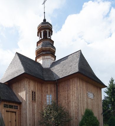 Zdjęcie nr 24: Kościół św. Joachima w Skawinkach usytuowany jest w centrum wsi, na zachód od głównej drogi prowadzącej z Palczy do Kalwarii Zebrzydowskiej. Teren przykościelny jest usytuowany na wysokim wzniesieniu, do którego prowadzą trzy wejścia, jedno przez schody, drugie przez obszerny wjazd od strony południowej.

Kościół skierowany na zachód, drewniany o konstrukcji zrębowej, na rzucie krzyża greckiego ze ściętymi kątami międzyramiennymi.  Przy prezbiterium zakrystia. Strop wsparty na czterech parach słupów, ustawionych w krzyżu kościoła, w licu ścian ramienia wschodniego i zachodniego. Belka tęczy prosta, profilowana na kroksztynach, na niej Grupa Ukrzyżowania. Świątynia połączona za pomocą kruchty z wieżą o konstrukcji słupowej, na planie kwadratu z nadwieszoną izbicą, nakryta dachem namiotowym, ściany dzwonnicy opasane mniej więcej w połowie wysokości pulpitowym daszkiem, zlewającym się po bokach z siodłowym dachem kruchty. Do kościoła prowadzi główne wejście w przedsionku od strony południowej. Wnętrze świątyni oświetlają prostokątne okna. Dach nakryty gontem, na skrzyżowaniu ramiona krzyża greckiego wystawiona wieżyczka na sygnaturkę z latarnią. Ściany na zewnątrz pokryte szalunkiem pionowym.
