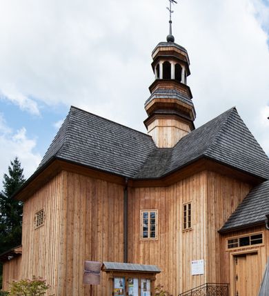 Zdjęcie nr 30: Kościół św. Joachima w Skawinkach usytuowany jest w centrum wsi, na zachód od głównej drogi prowadzącej z Palczy do Kalwarii Zebrzydowskiej. Teren przykościelny jest usytuowany na wysokim wzniesieniu, do którego prowadzą trzy wejścia, jedno przez schody, drugie przez obszerny wjazd od strony południowej.

Kościół skierowany na zachód, drewniany o konstrukcji zrębowej, na rzucie krzyża greckiego ze ściętymi kątami międzyramiennymi.  Przy prezbiterium zakrystia. Strop wsparty na czterech parach słupów, ustawionych w krzyżu kościoła, w licu ścian ramienia wschodniego i zachodniego. Belka tęczy prosta, profilowana na kroksztynach, na niej Grupa Ukrzyżowania. Świątynia połączona za pomocą kruchty z wieżą o konstrukcji słupowej, na planie kwadratu z nadwieszoną izbicą, nakryta dachem namiotowym, ściany dzwonnicy opasane mniej więcej w połowie wysokości pulpitowym daszkiem, zlewającym się po bokach z siodłowym dachem kruchty. Do kościoła prowadzi główne wejście w przedsionku od strony południowej. Wnętrze świątyni oświetlają prostokątne okna. Dach nakryty gontem, na skrzyżowaniu ramiona krzyża greckiego wystawiona wieżyczka na sygnaturkę z latarnią. Ściany na zewnątrz pokryte szalunkiem pionowym.
