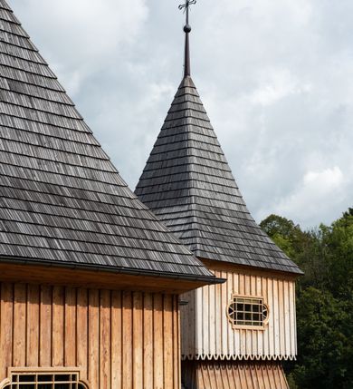 Zdjęcie nr 34: Kościół św. Joachima w Skawinkach usytuowany jest w centrum wsi, na zachód od głównej drogi prowadzącej z Palczy do Kalwarii Zebrzydowskiej. Teren przykościelny jest usytuowany na wysokim wzniesieniu, do którego prowadzą trzy wejścia, jedno przez schody, drugie przez obszerny wjazd od strony południowej.

Kościół skierowany na zachód, drewniany o konstrukcji zrębowej, na rzucie krzyża greckiego ze ściętymi kątami międzyramiennymi.  Przy prezbiterium zakrystia. Strop wsparty na czterech parach słupów, ustawionych w krzyżu kościoła, w licu ścian ramienia wschodniego i zachodniego. Belka tęczy prosta, profilowana na kroksztynach, na niej Grupa Ukrzyżowania. Świątynia połączona za pomocą kruchty z wieżą o konstrukcji słupowej, na planie kwadratu z nadwieszoną izbicą, nakryta dachem namiotowym, ściany dzwonnicy opasane mniej więcej w połowie wysokości pulpitowym daszkiem, zlewającym się po bokach z siodłowym dachem kruchty. Do kościoła prowadzi główne wejście w przedsionku od strony południowej. Wnętrze świątyni oświetlają prostokątne okna. Dach nakryty gontem, na skrzyżowaniu ramiona krzyża greckiego wystawiona wieżyczka na sygnaturkę z latarnią. Ściany na zewnątrz pokryte szalunkiem pionowym.
