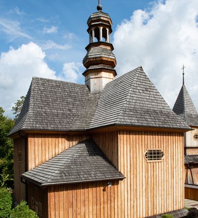 Zdjęcie nr 36: Kościół św. Joachima w Skawinkach usytuowany jest w centrum wsi, na zachód od głównej drogi prowadzącej z Palczy do Kalwarii Zebrzydowskiej. Teren przykościelny jest usytuowany na wysokim wzniesieniu, do którego prowadzą trzy wejścia, jedno przez schody, drugie przez obszerny wjazd od strony południowej.

Kościół skierowany na zachód, drewniany o konstrukcji zrębowej, na rzucie krzyża greckiego ze ściętymi kątami międzyramiennymi.  Przy prezbiterium zakrystia. Strop wsparty na czterech parach słupów, ustawionych w krzyżu kościoła, w licu ścian ramienia wschodniego i zachodniego. Belka tęczy prosta, profilowana na kroksztynach, na niej Grupa Ukrzyżowania. Świątynia połączona za pomocą kruchty z wieżą o konstrukcji słupowej, na planie kwadratu z nadwieszoną izbicą, nakryta dachem namiotowym, ściany dzwonnicy opasane mniej więcej w połowie wysokości pulpitowym daszkiem, zlewającym się po bokach z siodłowym dachem kruchty. Do kościoła prowadzi główne wejście w przedsionku od strony południowej. Wnętrze świątyni oświetlają prostokątne okna. Dach nakryty gontem, na skrzyżowaniu ramiona krzyża greckiego wystawiona wieżyczka na sygnaturkę z latarnią. Ściany na zewnątrz pokryte szalunkiem pionowym.
