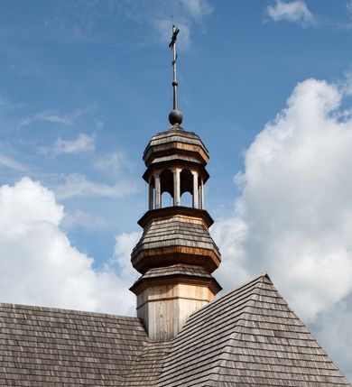 Zdjęcie nr 39: Kościół św. Joachima w Skawinkach usytuowany jest w centrum wsi, na zachód od głównej drogi prowadzącej z Palczy do Kalwarii Zebrzydowskiej. Teren przykościelny jest usytuowany na wysokim wzniesieniu, do którego prowadzą trzy wejścia, jedno przez schody, drugie przez obszerny wjazd od strony południowej.

Kościół skierowany na zachód, drewniany o konstrukcji zrębowej, na rzucie krzyża greckiego ze ściętymi kątami międzyramiennymi.  Przy prezbiterium zakrystia. Strop wsparty na czterech parach słupów, ustawionych w krzyżu kościoła, w licu ścian ramienia wschodniego i zachodniego. Belka tęczy prosta, profilowana na kroksztynach, na niej Grupa Ukrzyżowania. Świątynia połączona za pomocą kruchty z wieżą o konstrukcji słupowej, na planie kwadratu z nadwieszoną izbicą, nakryta dachem namiotowym, ściany dzwonnicy opasane mniej więcej w połowie wysokości pulpitowym daszkiem, zlewającym się po bokach z siodłowym dachem kruchty. Do kościoła prowadzi główne wejście w przedsionku od strony południowej. Wnętrze świątyni oświetlają prostokątne okna. Dach nakryty gontem, na skrzyżowaniu ramiona krzyża greckiego wystawiona wieżyczka na sygnaturkę z latarnią. Ściany na zewnątrz pokryte szalunkiem pionowym.
