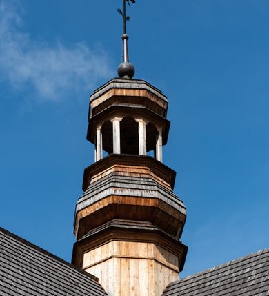 Zdjęcie nr 46: Kościół św. Joachima w Skawinkach usytuowany jest w centrum wsi, na zachód od głównej drogi prowadzącej z Palczy do Kalwarii Zebrzydowskiej. Teren przykościelny jest usytuowany na wysokim wzniesieniu, do którego prowadzą trzy wejścia, jedno przez schody, drugie przez obszerny wjazd od strony południowej.

Kościół skierowany na zachód, drewniany o konstrukcji zrębowej, na rzucie krzyża greckiego ze ściętymi kątami międzyramiennymi.  Przy prezbiterium zakrystia. Strop wsparty na czterech parach słupów, ustawionych w krzyżu kościoła, w licu ścian ramienia wschodniego i zachodniego. Belka tęczy prosta, profilowana na kroksztynach, na niej Grupa Ukrzyżowania. Świątynia połączona za pomocą kruchty z wieżą o konstrukcji słupowej, na planie kwadratu z nadwieszoną izbicą, nakryta dachem namiotowym, ściany dzwonnicy opasane mniej więcej w połowie wysokości pulpitowym daszkiem, zlewającym się po bokach z siodłowym dachem kruchty. Do kościoła prowadzi główne wejście w przedsionku od strony południowej. Wnętrze świątyni oświetlają prostokątne okna. Dach nakryty gontem, na skrzyżowaniu ramiona krzyża greckiego wystawiona wieżyczka na sygnaturkę z latarnią. Ściany na zewnątrz pokryte szalunkiem pionowym.
