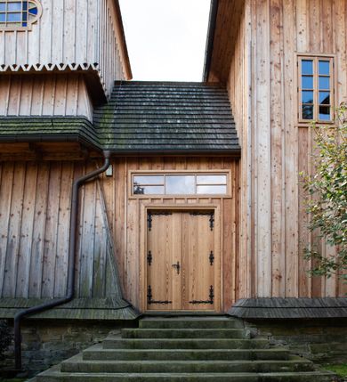 Zdjęcie nr 55: Kościół św. Joachima w Skawinkach usytuowany jest w centrum wsi, na zachód od głównej drogi prowadzącej z Palczy do Kalwarii Zebrzydowskiej. Teren przykościelny jest usytuowany na wysokim wzniesieniu, do którego prowadzą trzy wejścia, jedno przez schody, drugie przez obszerny wjazd od strony południowej.

Kościół skierowany na zachód, drewniany o konstrukcji zrębowej, na rzucie krzyża greckiego ze ściętymi kątami międzyramiennymi.  Przy prezbiterium zakrystia. Strop wsparty na czterech parach słupów, ustawionych w krzyżu kościoła, w licu ścian ramienia wschodniego i zachodniego. Belka tęczy prosta, profilowana na kroksztynach, na niej Grupa Ukrzyżowania. Świątynia połączona za pomocą kruchty z wieżą o konstrukcji słupowej, na planie kwadratu z nadwieszoną izbicą, nakryta dachem namiotowym, ściany dzwonnicy opasane mniej więcej w połowie wysokości pulpitowym daszkiem, zlewającym się po bokach z siodłowym dachem kruchty. Do kościoła prowadzi główne wejście w przedsionku od strony południowej. Wnętrze świątyni oświetlają prostokątne okna. Dach nakryty gontem, na skrzyżowaniu ramiona krzyża greckiego wystawiona wieżyczka na sygnaturkę z latarnią. Ściany na zewnątrz pokryte szalunkiem pionowym.
