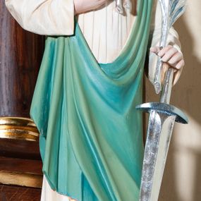 Zdjęcie nr 1: Figura pełna na cokole przedstawiająca św. Agnieszkę, która stoi frontalnie, kierując wzrok lekko w prawo. Ma owalną twarz, małe oczy, szeroki nos i małe usta oraz długie, falowane włosy, które opadają na ramiona i plecy; na głowie wianek z lilii. Prawą, uniesioną ręką przytrzymuje baranka, wyciągającego pyszczek w stronę liścia palmowego, który święta, razem z mieczem trzyma w lewej dłoni. Jest ubrana w białą suknię marszczoną pod szyją oraz zielony płaszcz przechodzący przez lewy bark i przytrzymany prawą ręką ponad biodrem. Polichromia w partiach ciała naturalistyczna.