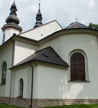 Zdjęcie nr 8: Kościół murowany, orientowany, z półkoliście zamkniętym prezbiterium, zakrystią od północy i kaplicą od południa, z przedsionkiem i wieżą od zachodu. Budynek trójnawowy, trójprzęsłowy, z nawą główną szerszą od bocznych, oddzieloną filarami, ze sklepieniem kolebkowym z gurtami. Od zachodu chór muzyczny wsparty na filarach. Ściany artykułowane pilastrami, do których dochodzą gurty sklepienia, prezbiterium oddzielone łukiem tęczowym z napisem „OTO BARANEK BOŻY”. Między pilastrami naw bocznych oraz po obu stronach ołtarza okna w kształcie stojącego prostokąta zamkniętego półkoliście. Mniejsze w kaplicy, zakrystii, przedsionku, oraz z czterech stron wieży. Główne drzwi od wschodu, boczne od północy, kolejne do zakrystii. 
Fasada trójosiowa, dwukondygnacyjna, zakończona wieżą z hełmem. Osie wydzielone są występami, kondygnacja artykułowana fragmentami gzymsu. W dolnej kondygnacji drzwi o wykroju prostokątnym, powyżej okulus. W osiach bocznych wąskie okna w kształcie stojącego prostokąta zamkniętego półkoliście, powyżej pod fragmentami gzymsu rzędy ornamentu kostkowego. W drugiej kondygnacji, na występującym fragmencie ściany tarcza zegara. Powyżej kondygnacja ośmiobocznej wieży, z czterech stron przeprutej wąskimi oknami o wykroju jak w fasadzie. Ściany boczne kościoła gładkie, przedsionek zaznaczony płaskimi lizenami, okna umieszczone we wnękach. Nawa główna, kaplica oraz kruchta nakryte dachami dwuspadowymi, prezbiterium dwuspadowym zamkniętym półkoliście. Wieża zwieńczona hełmem o rozbudowanej konstrukcji. Na zwężającym się dachu cebulasta kopuła zakończona latarnią przeprutą arkadkami zwieńczoną mniejszą kopułką cebulastą zakończoną krzyżem na kuli. 

Do najstarszych elementów wyposażenia należą kamienna siedemnastowieczna chrzcielnica, krucyfiks z tego samego okresu oraz osiemnastowieczna rzeźba Chrystusa Frasobliwego.