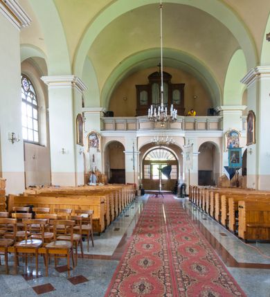 Zdjęcie nr 17: Kościół murowany, orientowany, z półkoliście zamkniętym prezbiterium, zakrystią od północy i kaplicą od południa, z przedsionkiem i wieżą od zachodu. Budynek trójnawowy, trójprzęsłowy, z nawą główną szerszą od bocznych, oddzieloną filarami, ze sklepieniem kolebkowym z gurtami. Od zachodu chór muzyczny wsparty na filarach. Ściany artykułowane pilastrami, do których dochodzą gurty sklepienia, prezbiterium oddzielone łukiem tęczowym z napisem „OTO BARANEK BOŻY”. Między pilastrami naw bocznych oraz po obu stronach ołtarza okna w kształcie stojącego prostokąta zamkniętego półkoliście. Mniejsze w kaplicy, zakrystii, przedsionku, oraz z czterech stron wieży. Główne drzwi od wschodu, boczne od północy, kolejne do zakrystii. 
Fasada trójosiowa, dwukondygnacyjna, zakończona wieżą z hełmem. Osie wydzielone są występami, kondygnacja artykułowana fragmentami gzymsu. W dolnej kondygnacji drzwi o wykroju prostokątnym, powyżej okulus. W osiach bocznych wąskie okna w kształcie stojącego prostokąta zamkniętego półkoliście, powyżej pod fragmentami gzymsu rzędy ornamentu kostkowego. W drugiej kondygnacji, na występującym fragmencie ściany tarcza zegara. Powyżej kondygnacja ośmiobocznej wieży, z czterech stron przeprutej wąskimi oknami o wykroju jak w fasadzie. Ściany boczne kościoła gładkie, przedsionek zaznaczony płaskimi lizenami, okna umieszczone we wnękach. Nawa główna, kaplica oraz kruchta nakryte dachami dwuspadowymi, prezbiterium dwuspadowym zamkniętym półkoliście. Wieża zwieńczona hełmem o rozbudowanej konstrukcji. Na zwężającym się dachu cebulasta kopuła zakończona latarnią przeprutą arkadkami zwieńczoną mniejszą kopułką cebulastą zakończoną krzyżem na kuli. 

Do najstarszych elementów wyposażenia należą kamienna siedemnastowieczna chrzcielnica, krucyfiks z tego samego okresu oraz osiemnastowieczna rzeźba Chrystusa Frasobliwego.