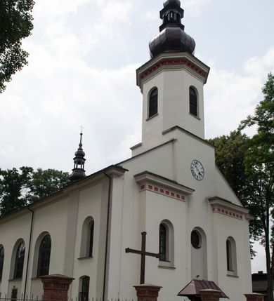 Zdjęcie nr 5: Kościół murowany, orientowany, z półkoliście zamkniętym prezbiterium, zakrystią od północy i kaplicą od południa, z przedsionkiem i wieżą od zachodu. Budynek trójnawowy, trójprzęsłowy, z nawą główną szerszą od bocznych, oddzieloną filarami, ze sklepieniem kolebkowym z gurtami. Od zachodu chór muzyczny wsparty na filarach. Ściany artykułowane pilastrami, do których dochodzą gurty sklepienia, prezbiterium oddzielone łukiem tęczowym z napisem „OTO BARANEK BOŻY”. Między pilastrami naw bocznych oraz po obu stronach ołtarza okna w kształcie stojącego prostokąta zamkniętego półkoliście. Mniejsze w kaplicy, zakrystii, przedsionku, oraz z czterech stron wieży. Główne drzwi od wschodu, boczne od północy, kolejne do zakrystii. 
Fasada trójosiowa, dwukondygnacyjna, zakończona wieżą z hełmem. Osie wydzielone są występami, kondygnacja artykułowana fragmentami gzymsu. W dolnej kondygnacji drzwi o wykroju prostokątnym, powyżej okulus. W osiach bocznych wąskie okna w kształcie stojącego prostokąta zamkniętego półkoliście, powyżej pod fragmentami gzymsu rzędy ornamentu kostkowego. W drugiej kondygnacji, na występującym fragmencie ściany tarcza zegara. Powyżej kondygnacja ośmiobocznej wieży, z czterech stron przeprutej wąskimi oknami o wykroju jak w fasadzie. Ściany boczne kościoła gładkie, przedsionek zaznaczony płaskimi lizenami, okna umieszczone we wnękach. Nawa główna, kaplica oraz kruchta nakryte dachami dwuspadowymi, prezbiterium dwuspadowym zamkniętym półkoliście. Wieża zwieńczona hełmem o rozbudowanej konstrukcji. Na zwężającym się dachu cebulasta kopuła zakończona latarnią przeprutą arkadkami zwieńczoną mniejszą kopułką cebulastą zakończoną krzyżem na kuli. 

Do najstarszych elementów wyposażenia należą kamienna siedemnastowieczna chrzcielnica, krucyfiks z tego samego okresu oraz osiemnastowieczna rzeźba Chrystusa Frasobliwego.