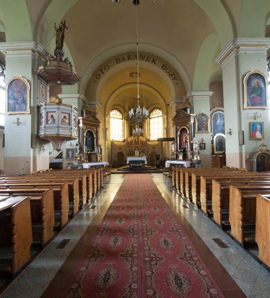 Zdjęcie nr 12: Kościół murowany, orientowany, z półkoliście zamkniętym prezbiterium, zakrystią od północy i kaplicą od południa, z przedsionkiem i wieżą od zachodu. Budynek trójnawowy, trójprzęsłowy, z nawą główną szerszą od bocznych, oddzieloną filarami, ze sklepieniem kolebkowym z gurtami. Od zachodu chór muzyczny wsparty na filarach. Ściany artykułowane pilastrami, do których dochodzą gurty sklepienia, prezbiterium oddzielone łukiem tęczowym z napisem „OTO BARANEK BOŻY”. Między pilastrami naw bocznych oraz po obu stronach ołtarza okna w kształcie stojącego prostokąta zamkniętego półkoliście. Mniejsze w kaplicy, zakrystii, przedsionku, oraz z czterech stron wieży. Główne drzwi od wschodu, boczne od północy, kolejne do zakrystii. 
Fasada trójosiowa, dwukondygnacyjna, zakończona wieżą z hełmem. Osie wydzielone są występami, kondygnacja artykułowana fragmentami gzymsu. W dolnej kondygnacji drzwi o wykroju prostokątnym, powyżej okulus. W osiach bocznych wąskie okna w kształcie stojącego prostokąta zamkniętego półkoliście, powyżej pod fragmentami gzymsu rzędy ornamentu kostkowego. W drugiej kondygnacji, na występującym fragmencie ściany tarcza zegara. Powyżej kondygnacja ośmiobocznej wieży, z czterech stron przeprutej wąskimi oknami o wykroju jak w fasadzie. Ściany boczne kościoła gładkie, przedsionek zaznaczony płaskimi lizenami, okna umieszczone we wnękach. Nawa główna, kaplica oraz kruchta nakryte dachami dwuspadowymi, prezbiterium dwuspadowym zamkniętym półkoliście. Wieża zwieńczona hełmem o rozbudowanej konstrukcji. Na zwężającym się dachu cebulasta kopuła zakończona latarnią przeprutą arkadkami zwieńczoną mniejszą kopułką cebulastą zakończoną krzyżem na kuli. 

Do najstarszych elementów wyposażenia należą kamienna siedemnastowieczna chrzcielnica, krucyfiks z tego samego okresu oraz osiemnastowieczna rzeźba Chrystusa Frasobliwego.