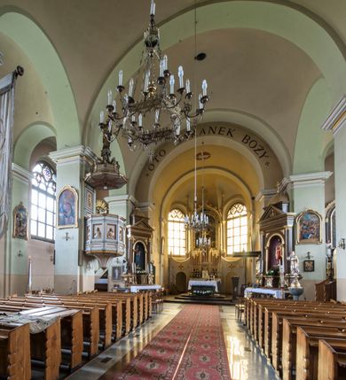 Zdjęcie nr 15: Kościół murowany, orientowany, z półkoliście zamkniętym prezbiterium, zakrystią od północy i kaplicą od południa, z przedsionkiem i wieżą od zachodu. Budynek trójnawowy, trójprzęsłowy, z nawą główną szerszą od bocznych, oddzieloną filarami, ze sklepieniem kolebkowym z gurtami. Od zachodu chór muzyczny wsparty na filarach. Ściany artykułowane pilastrami, do których dochodzą gurty sklepienia, prezbiterium oddzielone łukiem tęczowym z napisem „OTO BARANEK BOŻY”. Między pilastrami naw bocznych oraz po obu stronach ołtarza okna w kształcie stojącego prostokąta zamkniętego półkoliście. Mniejsze w kaplicy, zakrystii, przedsionku, oraz z czterech stron wieży. Główne drzwi od wschodu, boczne od północy, kolejne do zakrystii. 
Fasada trójosiowa, dwukondygnacyjna, zakończona wieżą z hełmem. Osie wydzielone są występami, kondygnacja artykułowana fragmentami gzymsu. W dolnej kondygnacji drzwi o wykroju prostokątnym, powyżej okulus. W osiach bocznych wąskie okna w kształcie stojącego prostokąta zamkniętego półkoliście, powyżej pod fragmentami gzymsu rzędy ornamentu kostkowego. W drugiej kondygnacji, na występującym fragmencie ściany tarcza zegara. Powyżej kondygnacja ośmiobocznej wieży, z czterech stron przeprutej wąskimi oknami o wykroju jak w fasadzie. Ściany boczne kościoła gładkie, przedsionek zaznaczony płaskimi lizenami, okna umieszczone we wnękach. Nawa główna, kaplica oraz kruchta nakryte dachami dwuspadowymi, prezbiterium dwuspadowym zamkniętym półkoliście. Wieża zwieńczona hełmem o rozbudowanej konstrukcji. Na zwężającym się dachu cebulasta kopuła zakończona latarnią przeprutą arkadkami zwieńczoną mniejszą kopułką cebulastą zakończoną krzyżem na kuli. 

Do najstarszych elementów wyposażenia należą kamienna siedemnastowieczna chrzcielnica, krucyfiks z tego samego okresu oraz osiemnastowieczna rzeźba Chrystusa Frasobliwego.
