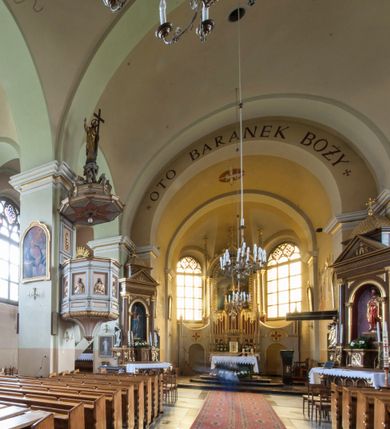 Zdjęcie nr 16: Kościół murowany, orientowany, z półkoliście zamkniętym prezbiterium, zakrystią od północy i kaplicą od południa, z przedsionkiem i wieżą od zachodu. Budynek trójnawowy, trójprzęsłowy, z nawą główną szerszą od bocznych, oddzieloną filarami, ze sklepieniem kolebkowym z gurtami. Od zachodu chór muzyczny wsparty na filarach. Ściany artykułowane pilastrami, do których dochodzą gurty sklepienia, prezbiterium oddzielone łukiem tęczowym z napisem „OTO BARANEK BOŻY”. Między pilastrami naw bocznych oraz po obu stronach ołtarza okna w kształcie stojącego prostokąta zamkniętego półkoliście. Mniejsze w kaplicy, zakrystii, przedsionku, oraz z czterech stron wieży. Główne drzwi od wschodu, boczne od północy, kolejne do zakrystii. 
Fasada trójosiowa, dwukondygnacyjna, zakończona wieżą z hełmem. Osie wydzielone są występami, kondygnacja artykułowana fragmentami gzymsu. W dolnej kondygnacji drzwi o wykroju prostokątnym, powyżej okulus. W osiach bocznych wąskie okna w kształcie stojącego prostokąta zamkniętego półkoliście, powyżej pod fragmentami gzymsu rzędy ornamentu kostkowego. W drugiej kondygnacji, na występującym fragmencie ściany tarcza zegara. Powyżej kondygnacja ośmiobocznej wieży, z czterech stron przeprutej wąskimi oknami o wykroju jak w fasadzie. Ściany boczne kościoła gładkie, przedsionek zaznaczony płaskimi lizenami, okna umieszczone we wnękach. Nawa główna, kaplica oraz kruchta nakryte dachami dwuspadowymi, prezbiterium dwuspadowym zamkniętym półkoliście. Wieża zwieńczona hełmem o rozbudowanej konstrukcji. Na zwężającym się dachu cebulasta kopuła zakończona latarnią przeprutą arkadkami zwieńczoną mniejszą kopułką cebulastą zakończoną krzyżem na kuli. 

Do najstarszych elementów wyposażenia należą kamienna siedemnastowieczna chrzcielnica, krucyfiks z tego samego okresu oraz osiemnastowieczna rzeźba Chrystusa Frasobliwego.