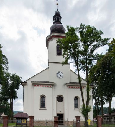Zdjęcie nr 4: Kościół murowany, orientowany, z półkoliście zamkniętym prezbiterium, zakrystią od północy i kaplicą od południa, z przedsionkiem i wieżą od zachodu. Budynek trójnawowy, trójprzęsłowy, z nawą główną szerszą od bocznych, oddzieloną filarami, ze sklepieniem kolebkowym z gurtami. Od zachodu chór muzyczny wsparty na filarach. Ściany artykułowane pilastrami, do których dochodzą gurty sklepienia, prezbiterium oddzielone łukiem tęczowym z napisem „OTO BARANEK BOŻY”. Między pilastrami naw bocznych oraz po obu stronach ołtarza okna w kształcie stojącego prostokąta zamkniętego półkoliście. Mniejsze w kaplicy, zakrystii, przedsionku, oraz z czterech stron wieży. Główne drzwi od wschodu, boczne od północy, kolejne do zakrystii. 
Fasada trójosiowa, dwukondygnacyjna, zakończona wieżą z hełmem. Osie wydzielone są występami, kondygnacja artykułowana fragmentami gzymsu. W dolnej kondygnacji drzwi o wykroju prostokątnym, powyżej okulus. W osiach bocznych wąskie okna w kształcie stojącego prostokąta zamkniętego półkoliście, powyżej pod fragmentami gzymsu rzędy ornamentu kostkowego. W drugiej kondygnacji, na występującym fragmencie ściany tarcza zegara. Powyżej kondygnacja ośmiobocznej wieży, z czterech stron przeprutej wąskimi oknami o wykroju jak w fasadzie. Ściany boczne kościoła gładkie, przedsionek zaznaczony płaskimi lizenami, okna umieszczone we wnękach. Nawa główna, kaplica oraz kruchta nakryte dachami dwuspadowymi, prezbiterium dwuspadowym zamkniętym półkoliście. Wieża zwieńczona hełmem o rozbudowanej konstrukcji. Na zwężającym się dachu cebulasta kopuła zakończona latarnią przeprutą arkadkami zwieńczoną mniejszą kopułką cebulastą zakończoną krzyżem na kuli. 

Do najstarszych elementów wyposażenia należą kamienna siedemnastowieczna chrzcielnica, krucyfiks z tego samego okresu oraz osiemnastowieczna rzeźba Chrystusa Frasobliwego.