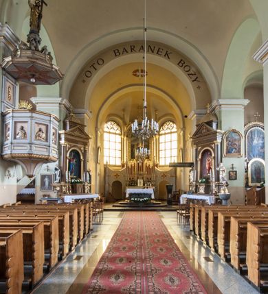 Zdjęcie nr 13: Kościół murowany, orientowany, z półkoliście zamkniętym prezbiterium, zakrystią od północy i kaplicą od południa, z przedsionkiem i wieżą od zachodu. Budynek trójnawowy, trójprzęsłowy, z nawą główną szerszą od bocznych, oddzieloną filarami, ze sklepieniem kolebkowym z gurtami. Od zachodu chór muzyczny wsparty na filarach. Ściany artykułowane pilastrami, do których dochodzą gurty sklepienia, prezbiterium oddzielone łukiem tęczowym z napisem „OTO BARANEK BOŻY”. Między pilastrami naw bocznych oraz po obu stronach ołtarza okna w kształcie stojącego prostokąta zamkniętego półkoliście. Mniejsze w kaplicy, zakrystii, przedsionku, oraz z czterech stron wieży. Główne drzwi od wschodu, boczne od północy, kolejne do zakrystii. 
Fasada trójosiowa, dwukondygnacyjna, zakończona wieżą z hełmem. Osie wydzielone są występami, kondygnacja artykułowana fragmentami gzymsu. W dolnej kondygnacji drzwi o wykroju prostokątnym, powyżej okulus. W osiach bocznych wąskie okna w kształcie stojącego prostokąta zamkniętego półkoliście, powyżej pod fragmentami gzymsu rzędy ornamentu kostkowego. W drugiej kondygnacji, na występującym fragmencie ściany tarcza zegara. Powyżej kondygnacja ośmiobocznej wieży, z czterech stron przeprutej wąskimi oknami o wykroju jak w fasadzie. Ściany boczne kościoła gładkie, przedsionek zaznaczony płaskimi lizenami, okna umieszczone we wnękach. Nawa główna, kaplica oraz kruchta nakryte dachami dwuspadowymi, prezbiterium dwuspadowym zamkniętym półkoliście. Wieża zwieńczona hełmem o rozbudowanej konstrukcji. Na zwężającym się dachu cebulasta kopuła zakończona latarnią przeprutą arkadkami zwieńczoną mniejszą kopułką cebulastą zakończoną krzyżem na kuli. 

Do najstarszych elementów wyposażenia należą kamienna siedemnastowieczna chrzcielnica, krucyfiks z tego samego okresu oraz osiemnastowieczna rzeźba Chrystusa Frasobliwego.