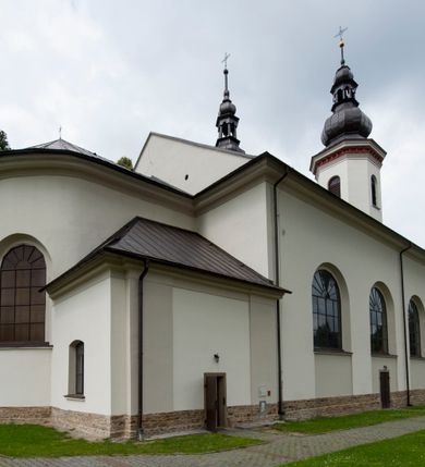 Zdjęcie nr 11: Kościół murowany, orientowany, z półkoliście zamkniętym prezbiterium, zakrystią od północy i kaplicą od południa, z przedsionkiem i wieżą od zachodu. Budynek trójnawowy, trójprzęsłowy, z nawą główną szerszą od bocznych, oddzieloną filarami, ze sklepieniem kolebkowym z gurtami. Od zachodu chór muzyczny wsparty na filarach. Ściany artykułowane pilastrami, do których dochodzą gurty sklepienia, prezbiterium oddzielone łukiem tęczowym z napisem „OTO BARANEK BOŻY”. Między pilastrami naw bocznych oraz po obu stronach ołtarza okna w kształcie stojącego prostokąta zamkniętego półkoliście. Mniejsze w kaplicy, zakrystii, przedsionku, oraz z czterech stron wieży. Główne drzwi od wschodu, boczne od północy, kolejne do zakrystii. 
Fasada trójosiowa, dwukondygnacyjna, zakończona wieżą z hełmem. Osie wydzielone są występami, kondygnacja artykułowana fragmentami gzymsu. W dolnej kondygnacji drzwi o wykroju prostokątnym, powyżej okulus. W osiach bocznych wąskie okna w kształcie stojącego prostokąta zamkniętego półkoliście, powyżej pod fragmentami gzymsu rzędy ornamentu kostkowego. W drugiej kondygnacji, na występującym fragmencie ściany tarcza zegara. Powyżej kondygnacja ośmiobocznej wieży, z czterech stron przeprutej wąskimi oknami o wykroju jak w fasadzie. Ściany boczne kościoła gładkie, przedsionek zaznaczony płaskimi lizenami, okna umieszczone we wnękach. Nawa główna, kaplica oraz kruchta nakryte dachami dwuspadowymi, prezbiterium dwuspadowym zamkniętym półkoliście. Wieża zwieńczona hełmem o rozbudowanej konstrukcji. Na zwężającym się dachu cebulasta kopuła zakończona latarnią przeprutą arkadkami zwieńczoną mniejszą kopułką cebulastą zakończoną krzyżem na kuli. 

Do najstarszych elementów wyposażenia należą kamienna siedemnastowieczna chrzcielnica, krucyfiks z tego samego okresu oraz osiemnastowieczna rzeźba Chrystusa Frasobliwego.