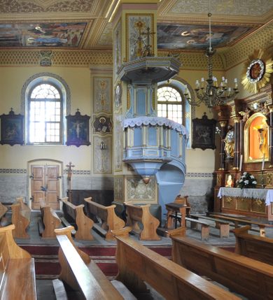 Zdjęcie nr 2: Kościół murowany, orientowany, z półkoliście zamkniętym prezbiterium, niewielką zakrystią od północy, z przedsionkiem i wieżą od zachodu. Budynek trójnawowy, trójprzęsłowy, z nawą główną szerszą od bocznych, oddzieloną filarami, ze sklepieniem zwierciadlanym. Prezbiterium oddzielone łukiem tęczowym, dwuprzęsłowe, nakryte sklepieniem żaglastym z gurtami. Od zachodu chór muzyczny wsparty na ściankach i filarach przechodzących w pilastry. Ściany artykułowane płaskimi pilastrami. Ściany, podpory oraz sklepienie pokryte polichromią.
Między pilastrami naw bocznych oraz po obu stronach ołtarza okna w kształcie stojącego prostokąta zamkniętego półkoliście. Dwa mniejsze okna w przedsionku, po jednym w drugiej i trzeciej kondygnacji wieży od zachodu, w czwartej kondygnacji z czterech stron. Główne drzwi od wschodu, boczne od północy, kolejne do północy do zakrystii. 
Fasada kościoła trójosiowa, czterokondygnacyjna, z wieżą na osi. Osie wydzielone są lizenami na narożach występu wieży, kondygnacje artykułowane otworami. Do wejścia prowadzą  drzwi w kształcie stojącego prostokąta w niszy zamkniętej łukiem koszowym, w drugiej kondygnacji balkon, w którym na tle okna figura Marii. W osiach bocznych wąskie okna w kształcie stojącego prostokąta zamkniętego półkoliście. Kondygnacje oddzielone niezbyt wydatnym gzymsem. Dwie górne kondygnacje przeprute oknami, w ostatniej kondygnacji wieża przechodzi w ośmioboczną. Tynkowane ściany boczne naw oraz prezbiterium artykułowane murowanymi z kamienia lizenami, pomiędzy którymi są okna umieszczone we wnękach. Nawa główna oraz kruchta nakryte dachami dwuspadowymi, prezbiterium dwuspadowym zamkniętym półkoliście. Wieża zwieńczona hełmem w formie ostrosłupa z trójkątnymi wycięciami powyżej okien ostatniej kondygnacji. Pod kościołem znajduje się wymurowania z kamienia grota, do której spływa woda ze słynącego cudami źródła. W grocie ustawiono figurę Matki Boskiej. 
Całe wyposażenie pochodzi z drugiej połowy XIX wieku. 