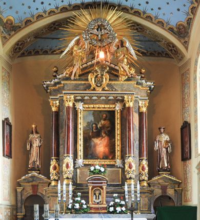 Zdjęcie nr 1: Nastawa ołtarzowa architektoniczna, jednoosiowa, jednokondygnacyjna, z bramkami, na cokole. Mensa skrzyniowa z dekorowanym antepedium. Nastawa na wysokim, pięciodzielnym cokole, którego druga i czwarta część są wysunięte do przodu. Pole główne ujęte parą pilastrów za dwiema parami kolumn dekorowanych do jednej trzeciej wysokości motywami złożonymi z ornamentów roślinnych z kaboszonami pośrodku, o kapitelach kompozytowych, dźwigających imposty i gzyms wyłamany do przodu. Środkowa para wysunięta przed lico ołtarza, zwieńczona trójkątnym przyczółkiem z kartuszem herbowym utworzonym z małżowiny z monogramem maryjnym pośrodku. Pole główne z obrazem Marii z rodzicami wymiennie z wizerunkiem Matki Boskiej Częstochowskiej i Matki Boskiej Fatimskiej w szerokiej, ażurowej, złoconej ramie. 
Zwieńczenie przyjmuje kształt glorii promienistej, w której centrum znajduje się gołębica w otoczeniu obłoków adorowana przez dwa anioły wspierające się na belkowaniu; na zewnętrznych fragmentach belkowania wazony płomieniste.  
Na bramkach przeprutych łukiem podkowiastym i zwieńczonych trójkątnym przyczółkiem posadowione na cokołach figury św. Kazimierza po lewej i św. Jana z Kęt po prawej. 
Nastawa marmoryzowana na kolor szary, płyciny na kolor beżowy, kolumny i niektóre detale na bordowo, większość detali ornamentyki złocona. Polichromia rzeźby w partiach ciała naturalistyczna.