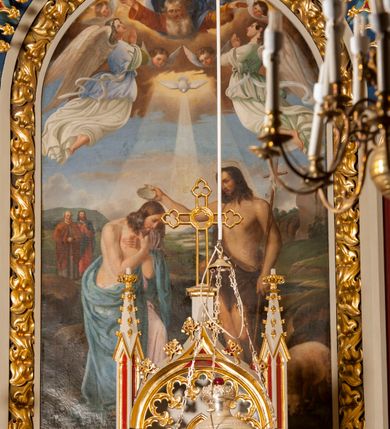 Zdjęcie nr 4: Ołtarz przyścienny z obejściem, złożony z mensy, predelli, bramek i nastawy. Mensa sarkofagowa, z kamiennym blatem, antepedium haftowane w motywy roślinne, z barankiem paschalnym w centrum. Predella dwukondygnacyjna, trójosiowa, osie rozdzielają zdwojone kolumny na wysokich konsolach, wychodzące przed lico predelli. W dolnej partii, części boczne dekorowane płycinami o kształcie zbliżonym do kwadratu, złożone z czworoliści, w polu środkowym prostopadłościenne tabernakulum, z drzwiczkami dekorowanymi groszowaniem i umieszczonym na jego tle motywem zdwojonego łuku ostrego z wpisanym monogramem IHS. Górna kondygnacja predelli oddzielona gzymsem, złożona z trzech zakończonych ostrołukowo blend w centrum i pięciu płycin różnej wysokości w częściach bocznych, flankowana pinaklami. Oś środkowa zakończona łukiem w ośli grzbiet nałożonym na łuk okrągły, zdobionym żabkami i zwieńczona krzyżem, flankowanym pinaklami z żabkami i kwiatonem. Do predelli przylegają z dwóch stron bramki prostokątne, zamknięte od góry łukiem odwróconym i flankowane pinaklem zakończonym kwiatonem. W bramkach wycięty otwór w kształcie prostokąta zamkniętego łukiem pełnym, powyżej którego umieszczono okrągłą plakietę wypełnioną motywem czworoliścia z wpisanymi łukami podkowiastymi. Plakietę ujmuje od góry łuk nadwieszony stykający się w środkowej części ze wspomnianym łukiem odwróconym. Nastawa znajduje się za predellą. Widoczna część składa się z pola flankowanego smukłymi kolumnami o kapitelach utworzonych z motywów roślinnych, na których skośnie ustawiono pinakle zdobione żabkami i zwieńczone kwiatonami. Na kolumnach wspiera się łuk w ośli grzbiet zdobiony od dołu ażurową koronką, a od góry żabkami i zwieńczony krzyżem. Za kolumnami ustawiono niższe, smuklejsze i skręcone, nakryte baldachimami z wyciętymi łukami ostrymi. Pole nastawy wypełnia obraz z przedstawieniem chrztu Chrystusa w kształcie stojącego prostokąta zamkniętego półkoliście w ramie utworzonej z mięsistych liści. 
Powierzchnia ołtarza w kolorze białym, wnętrza płycin czerwone, profile, detale i ornamenty złocone, wnętrze arkady nastawy niebieskie. 