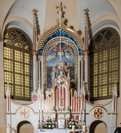 Zdjęcie nr 1: Ołtarz przyścienny z obejściem, złożony z mensy, predelli, bramek i nastawy. Mensa sarkofagowa, z kamiennym blatem, antepedium haftowane w motywy roślinne, z barankiem paschalnym w centrum. Predella dwukondygnacyjna, trójosiowa, osie rozdzielają zdwojone kolumny na wysokich konsolach, wychodzące przed lico predelli. W dolnej partii, części boczne dekorowane płycinami o kształcie zbliżonym do kwadratu, złożone z czworoliści, w polu środkowym prostopadłościenne tabernakulum, z drzwiczkami dekorowanymi groszowaniem i umieszczonym na jego tle motywem zdwojonego łuku ostrego z wpisanym monogramem IHS. Górna kondygnacja predelli oddzielona gzymsem, złożona z trzech zakończonych ostrołukowo blend w centrum i pięciu płycin różnej wysokości w częściach bocznych, flankowana pinaklami. Oś środkowa zakończona łukiem w ośli grzbiet nałożonym na łuk okrągły, zdobionym żabkami i zwieńczona krzyżem, flankowanym pinaklami z żabkami i kwiatonem. Do predelli przylegają z dwóch stron bramki prostokątne, zamknięte od góry łukiem odwróconym i flankowane pinaklem zakończonym kwiatonem. W bramkach wycięty otwór w kształcie prostokąta zamkniętego łukiem pełnym, powyżej którego umieszczono okrągłą plakietę wypełnioną motywem czworoliścia z wpisanymi łukami podkowiastymi. Plakietę ujmuje od góry łuk nadwieszony stykający się w środkowej części ze wspomnianym łukiem odwróconym. Nastawa znajduje się za predellą. Widoczna część składa się z pola flankowanego smukłymi kolumnami o kapitelach utworzonych z motywów roślinnych, na których skośnie ustawiono pinakle zdobione żabkami i zwieńczone kwiatonami. Na kolumnach wspiera się łuk w ośli grzbiet zdobiony od dołu ażurową koronką, a od góry żabkami i zwieńczony krzyżem. Za kolumnami ustawiono niższe, smuklejsze i skręcone, nakryte baldachimami z wyciętymi łukami ostrymi. Pole nastawy wypełnia obraz z przedstawieniem chrztu Chrystusa w kształcie stojącego prostokąta zamkniętego półkoliście w ramie utworzonej z mięsistych liści. 
Powierzchnia ołtarza w kolorze białym, wnętrza płycin czerwone, profile, detale i ornamenty złocone, wnętrze arkady nastawy niebieskie. 