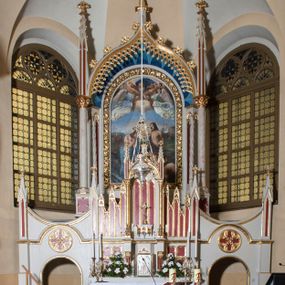 Zdjęcie nr 1: Ołtarz przyścienny z obejściem, złożony z mensy, predelli, bramek i nastawy. Mensa sarkofagowa, z kamiennym blatem, antepedium haftowane w motywy roślinne, z barankiem paschalnym w centrum. Predella dwukondygnacyjna, trójosiowa, osie rozdzielają zdwojone kolumny na wysokich konsolach, wychodzące przed lico predelli. W dolnej partii, części boczne dekorowane płycinami o kształcie zbliżonym do kwadratu, złożone z czworoliści, w polu środkowym prostopadłościenne tabernakulum, z drzwiczkami dekorowanymi groszowaniem i umieszczonym na jego tle motywem zdwojonego łuku ostrego z wpisanym monogramem IHS. Górna kondygnacja predelli oddzielona gzymsem, złożona z trzech zakończonych ostrołukowo blend w centrum i pięciu płycin różnej wysokości w częściach bocznych, flankowana pinaklami. Oś środkowa zakończona łukiem w ośli grzbiet nałożonym na łuk okrągły, zdobionym żabkami i zwieńczona krzyżem, flankowanym pinaklami z żabkami i kwiatonem. Do predelli przylegają z dwóch stron bramki prostokątne, zamknięte od góry łukiem odwróconym i flankowane pinaklem zakończonym kwiatonem. W bramkach wycięty otwór w kształcie prostokąta zamkniętego łukiem pełnym, powyżej którego umieszczono okrągłą plakietę wypełnioną motywem czworoliścia z wpisanymi łukami podkowiastymi. Plakietę ujmuje od góry łuk nadwieszony stykający się w środkowej części ze wspomnianym łukiem odwróconym. Nastawa znajduje się za predellą. Widoczna część składa się z pola flankowanego smukłymi kolumnami o kapitelach utworzonych z motywów roślinnych, na których skośnie ustawiono pinakle zdobione żabkami i zwieńczone kwiatonami. Na kolumnach wspiera się łuk w ośli grzbiet zdobiony od dołu ażurową koronką, a od góry żabkami i zwieńczony krzyżem. Za kolumnami ustawiono niższe, smuklejsze i skręcone, nakryte baldachimami z wyciętymi łukami ostrymi. Pole nastawy wypełnia obraz z przedstawieniem chrztu Chrystusa w kształcie stojącego prostokąta zamkniętego półkoliście w ramie utworzonej z mięsistych liści. 
Powierzchnia ołtarza w kolorze białym, wnętrza płycin czerwone, profile, detale i ornamenty złocone, wnętrze arkady nastawy niebieskie. 