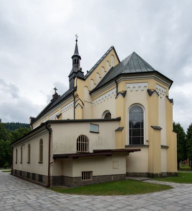 Zdjęcie nr 4: Kościół orientowany, jednonawowy, czteroprzęsłowy z niższym i węższym, jednoprzęsłowym prezbiterium zamkniętym wielobocznie. Od północnego wschodu do prezbiterium i nawy przylega zakrystia na rzucie prostokąta, od południowego wschodu prostokątna kruchta, a od zachodu kolejna prostokątna kruchta. W nawie sklepienie kolebkowe z lunetami, na zdwojonych gurtach przechodzących w pilastry o kompozytowych kapitelach i kanelowanych trzonach; w prezbiterium kolebkowe z lunetami na pojedynczych gurtach. Prezbiterium od nawy wydziela ściana tęczowa otwierająca się do wnętrza półkolistą arkadą. W ostatnim, zachodnim przęśle nawy chór muzyczny o ażurowej balustradzie, wsparty na dwóch smukłych, żeliwnych kolumnach. Otwory okienne w nawie i prezbiterium w kształcie stojącego prostokąta zamkniętego półkoliście. W ścianie zachodniej, w osi elewacji okno okrągłe. Fasada jednokondygnacyjna, jednoosiowa zamknięta trójkątną ścianą szczytową zwieńczoną krzyżem osadzonym na niewielkim daszku. W przyziemiu kruchta z otworem wejściowym w kształcie stojącego prostokąta zamkniętego łukiem półkolistym. Drzwi drewniane, dwuskrzydłowe z nadświetlem. Elewacja kruchty zamknięta schodkową ścianą szczytową zwieńczoną kamiennym krzyżem. Powyżej duże, okrągłe okno wypełnione rozetą, ujęte w motyw półkolistej arkady zaznaczonej w tynku. W górnej części fasady fryz arkadkowy. Elewacje boczne artykułowane uskokowymi przyporami, w górnej części dekorowane fryzem arkadowym. Nad nawą dach dwuspadowy, nad prezbiterium wielopołaciowy, ponad zakrystią oraz obiema kruchtami jednospadowy. Wszystkie kryte blachą. Ponad nawą umieszczona czworoboczna wieżyczka na sygnaturkę, z glorietą zwieńczoną ostrosłupowym hełmem. Na jej szczycie ażurowy krzyż. Elewacje świątyni tynkowane w odcieniach koloru żółtego oraz bieli.