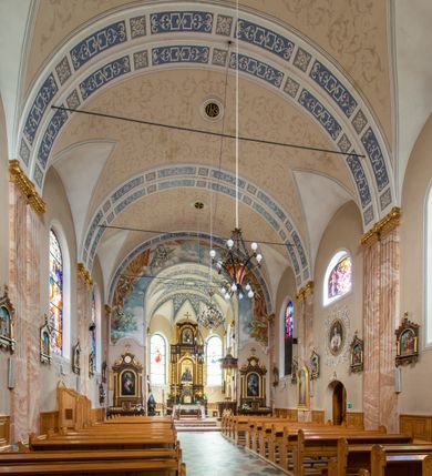 Zdjęcie nr 6: Kościół orientowany, jednonawowy, czteroprzęsłowy z niższym i węższym, jednoprzęsłowym prezbiterium zamkniętym wielobocznie. Od północnego wschodu do prezbiterium i nawy przylega zakrystia na rzucie prostokąta, od południowego wschodu prostokątna kruchta, a od zachodu kolejna prostokątna kruchta. W nawie sklepienie kolebkowe z lunetami, na zdwojonych gurtach przechodzących w pilastry o kompozytowych kapitelach i kanelowanych trzonach; w prezbiterium kolebkowe z lunetami na pojedynczych gurtach. Prezbiterium od nawy wydziela ściana tęczowa otwierająca się do wnętrza półkolistą arkadą. W ostatnim, zachodnim przęśle nawy chór muzyczny o ażurowej balustradzie, wsparty na dwóch smukłych, żeliwnych kolumnach. Otwory okienne w nawie i prezbiterium w kształcie stojącego prostokąta zamkniętego półkoliście. W ścianie zachodniej, w osi elewacji okno okrągłe. Fasada jednokondygnacyjna, jednoosiowa zamknięta trójkątną ścianą szczytową zwieńczoną krzyżem osadzonym na niewielkim daszku. W przyziemiu kruchta z otworem wejściowym w kształcie stojącego prostokąta zamkniętego łukiem półkolistym. Drzwi drewniane, dwuskrzydłowe z nadświetlem. Elewacja kruchty zamknięta schodkową ścianą szczytową zwieńczoną kamiennym krzyżem. Powyżej duże, okrągłe okno wypełnione rozetą, ujęte w motyw półkolistej arkady zaznaczonej w tynku. W górnej części fasady fryz arkadkowy. Elewacje boczne artykułowane uskokowymi przyporami, w górnej części dekorowane fryzem arkadowym. Nad nawą dach dwuspadowy, nad prezbiterium wielopołaciowy, ponad zakrystią oraz obiema kruchtami jednospadowy. Wszystkie kryte blachą. Ponad nawą umieszczona czworoboczna wieżyczka na sygnaturkę, z glorietą zwieńczoną ostrosłupowym hełmem. Na jej szczycie ażurowy krzyż. Elewacje świątyni tynkowane w odcieniach koloru żółtego oraz bieli.